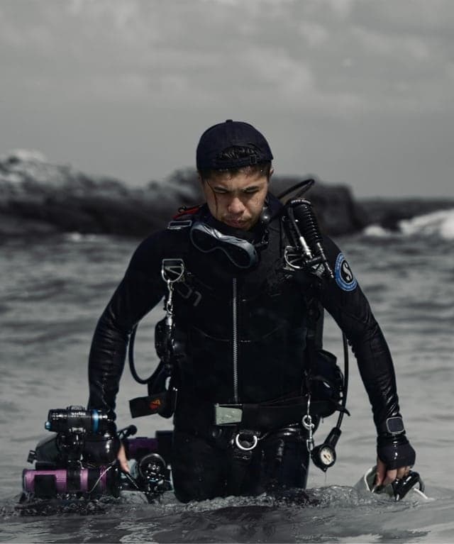 The founder of Dive Records walking out of the sea with an underwater camera
